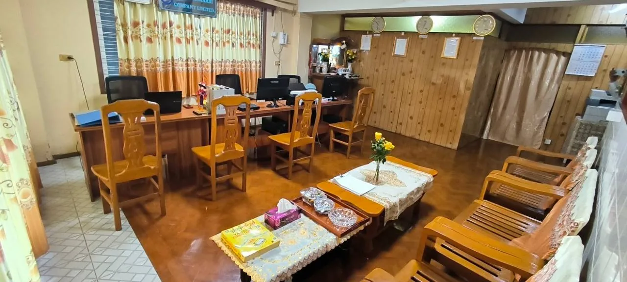 Interior of the office: desks with computers, wall clocks, framed documents on the wall and a seating area for visitors