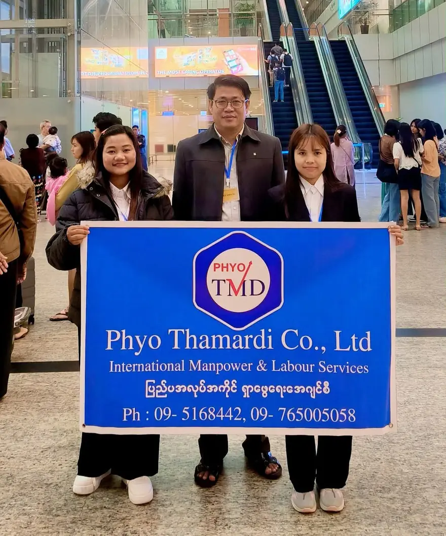 The Managing Director standing with two members of staff, the three of them holding a company banner reading Phyo Thamardi Co., Ltd — International Manpower and Labour Services